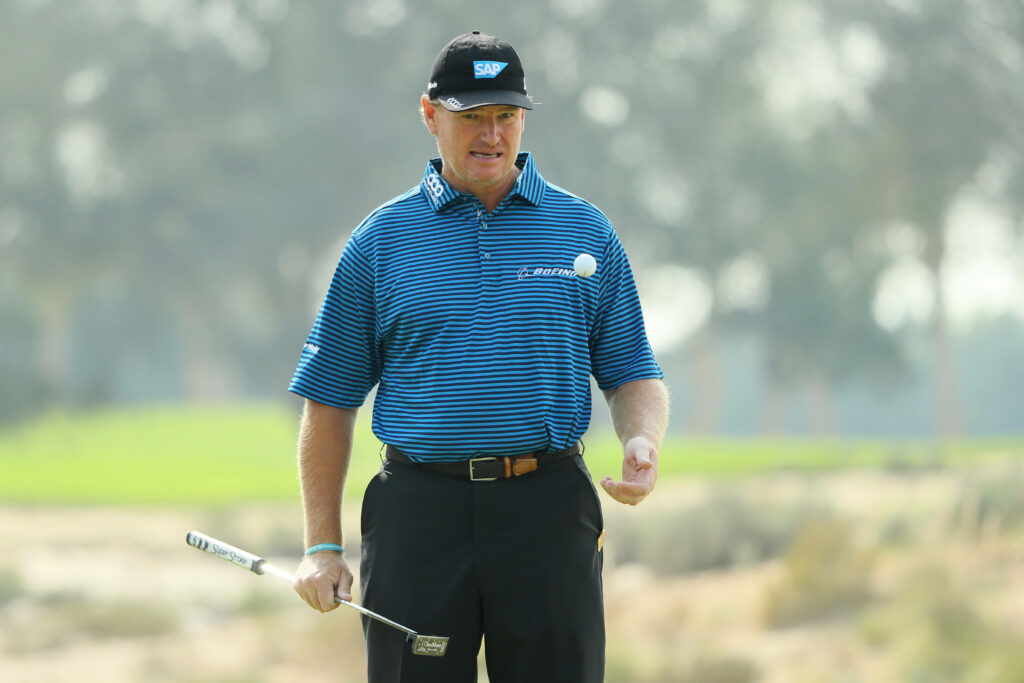 Ernie Els focused on lush golf course holding club wearing blue striped shirt and black cap Wallpaper
