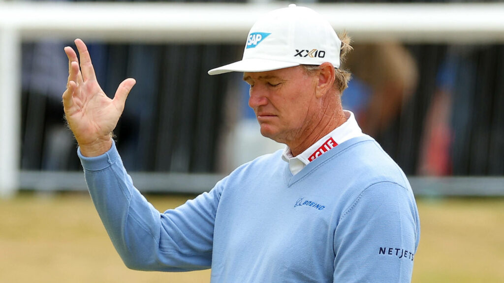 Ernie Els in light blue sweater raising hand on golf course showing calm focus and professionalism Wallpaper