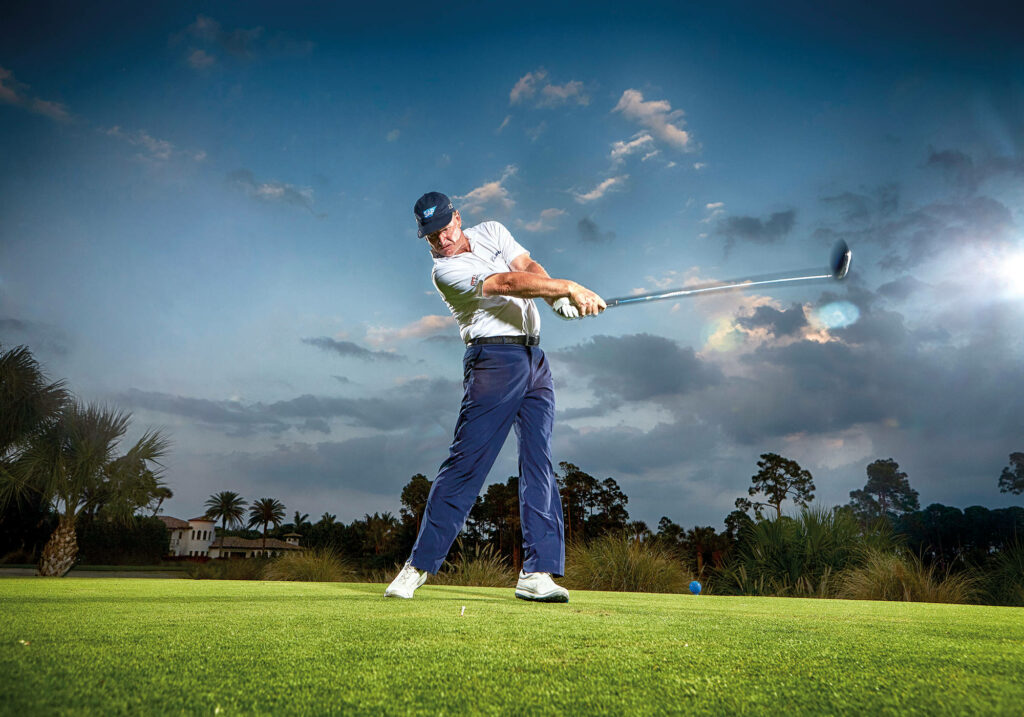 Ernie Els mid-swing on lush golf course with dramatic evening sky wide shot cinematic wallpaper