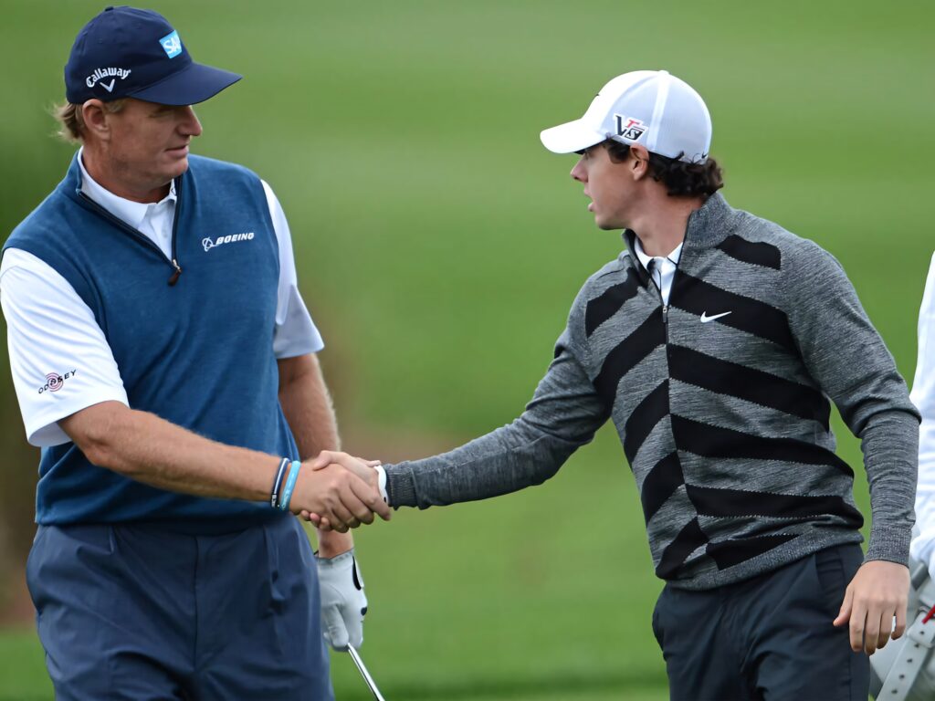 Ernie Els and Rory McIlroy shaking hands on lush golf course showing sportsmanship and respect Wallpaper