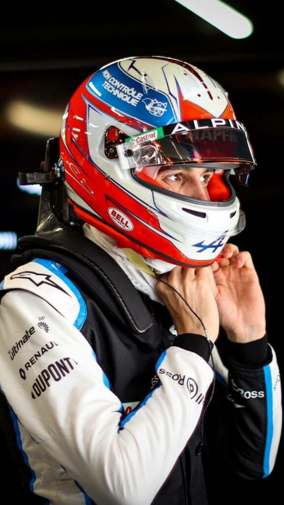Esteban Ocon close-up with vibrant Alpine helmet and detailed racing suit before F1 race wallpaper
