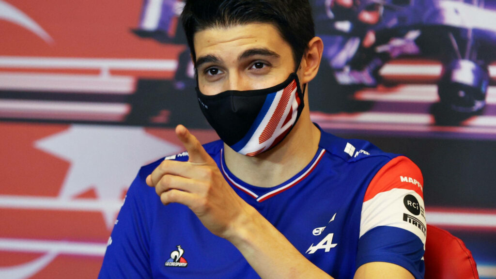 Esteban Ocon Alpine F1 driver in blue uniform with mask racing background red tones wallpaper