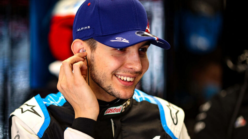 Esteban Ocon smiling in Alpine team garage wearing blue racing suit and cap high resolution Wallpaper