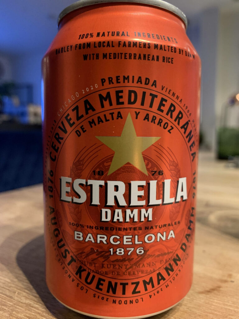 Close-up of scarlet red Estrella Damm beer can with golden star logo and Mediterranean design Wallpaper