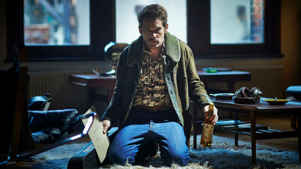 Ethan Hawke in Predestination movie wallpaper kneeling on rug holding bottle and case vintage room