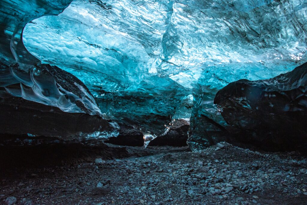 Ethereal blue ice cave with translucent ice arches and rugged stones natural wallpaper background