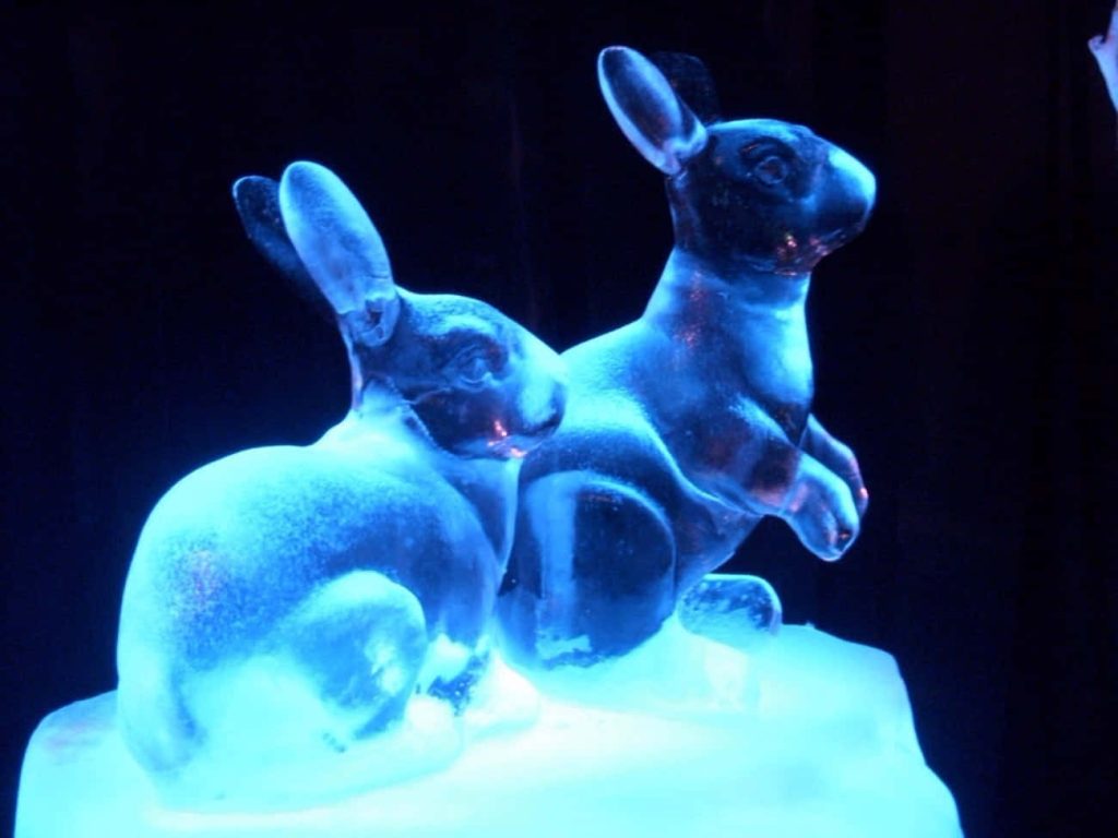 Ice sculpture of two rabbits glowing with blue light perfect winter wallpaper background