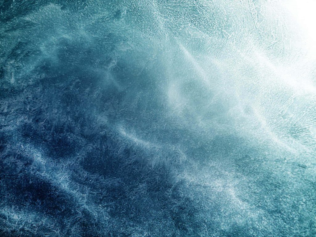 Macro ice wallpaper with intricate frost patterns in teal navy and glowing white light background