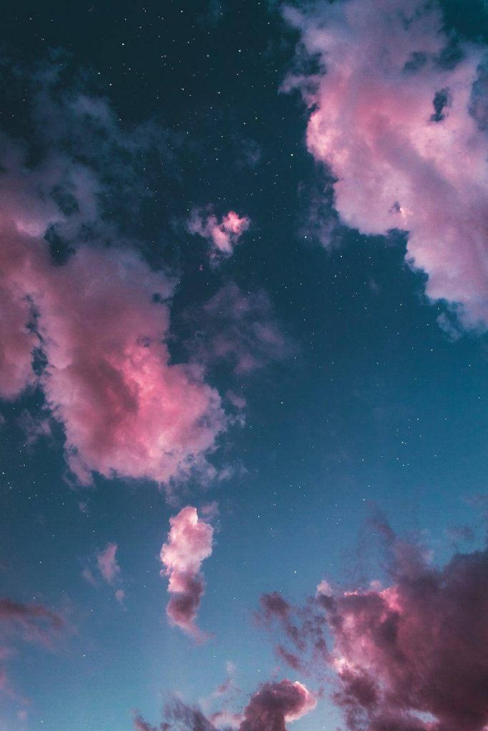 Vibrant magenta clouds glowing in a deep blue starry night sky celestial wallpaper background