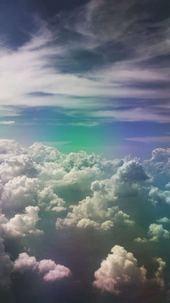 Ethereal wallpaper of fluffy porous clouds with soft rainbow hues and bright natural light sky