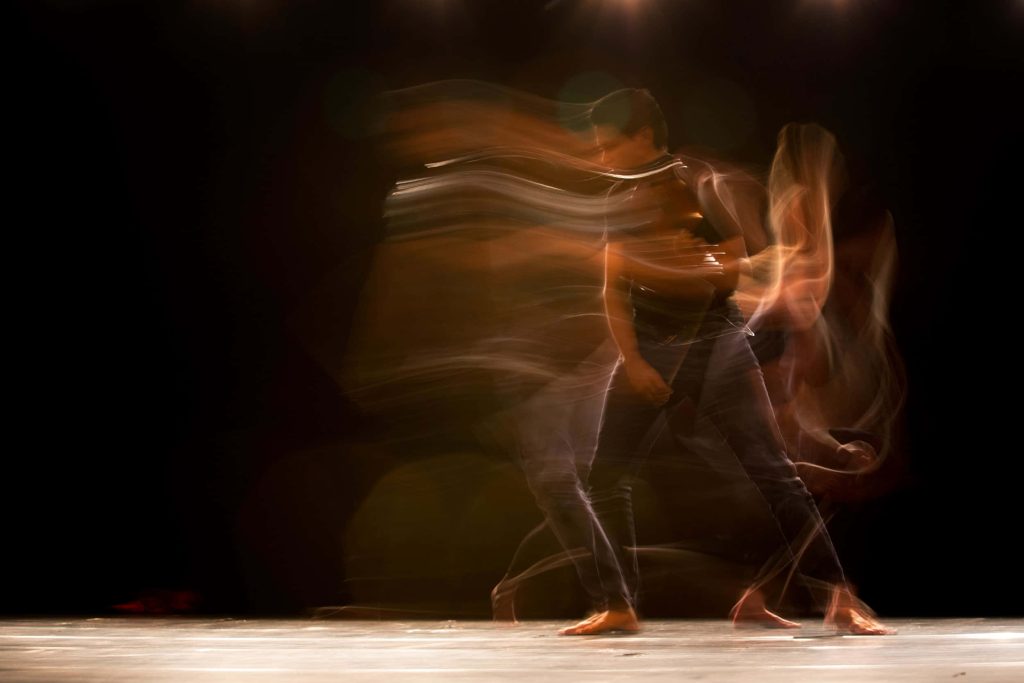 Man performing somatic stretching with long-exposure light trails on black exercise wallpaper background