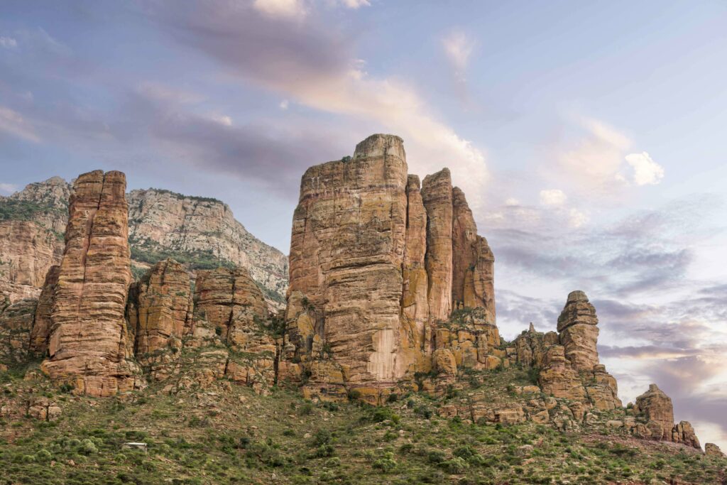 Ethiopian landscape wallpaper with towering rock formations lush greenery and pastel sky background