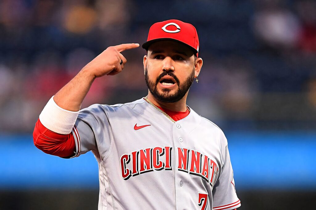 Eugenio Suárez Cincinnati Reds baseball player mid-action in red hat grey jersey stadium background Wallpaper