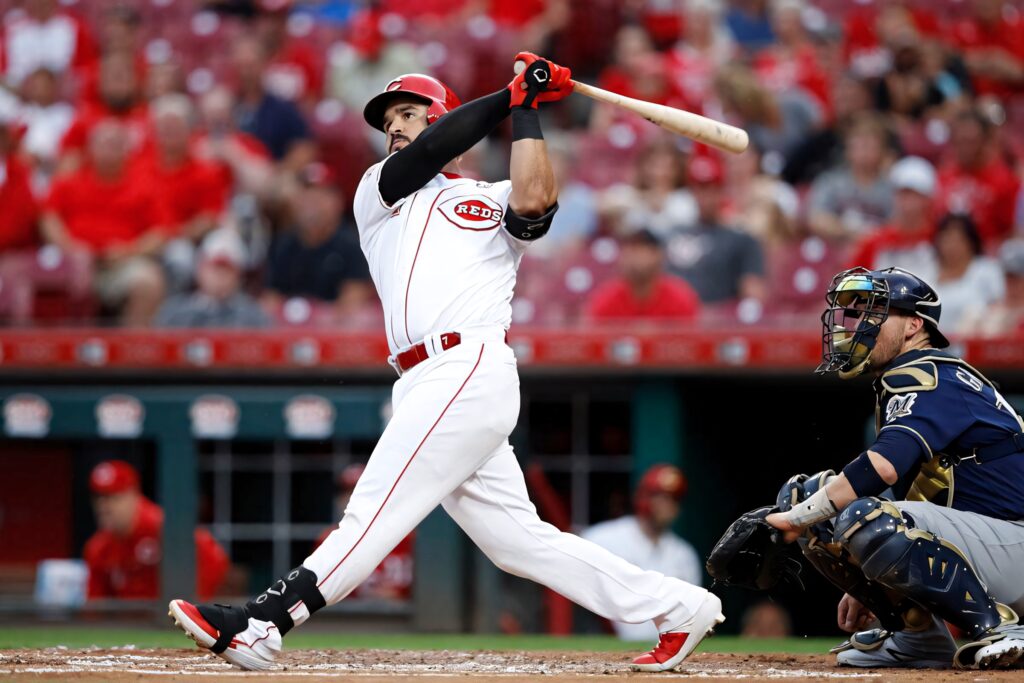 Eugenio Suarez Cincinnati Reds mid-swing dynamic baseball strike vibrant stadium background wallpaper