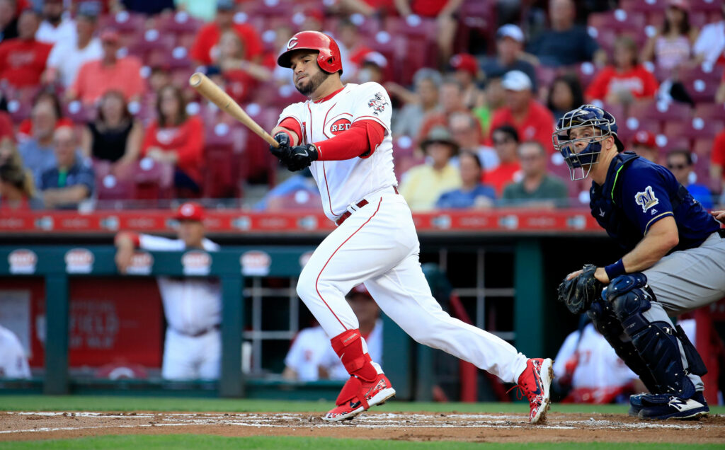 Eugenio Suárez in red and white gear focused on baseball field action with packed stadium background Wallpaper