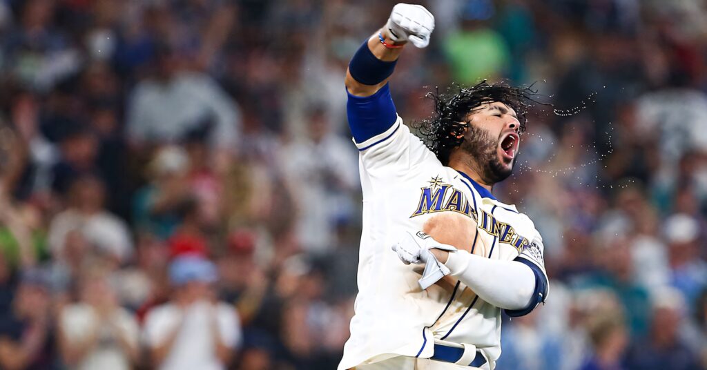 Eugenio Suárez in Mariners uniform celebrating passionately on field with vibrant crowd background Wallpaper