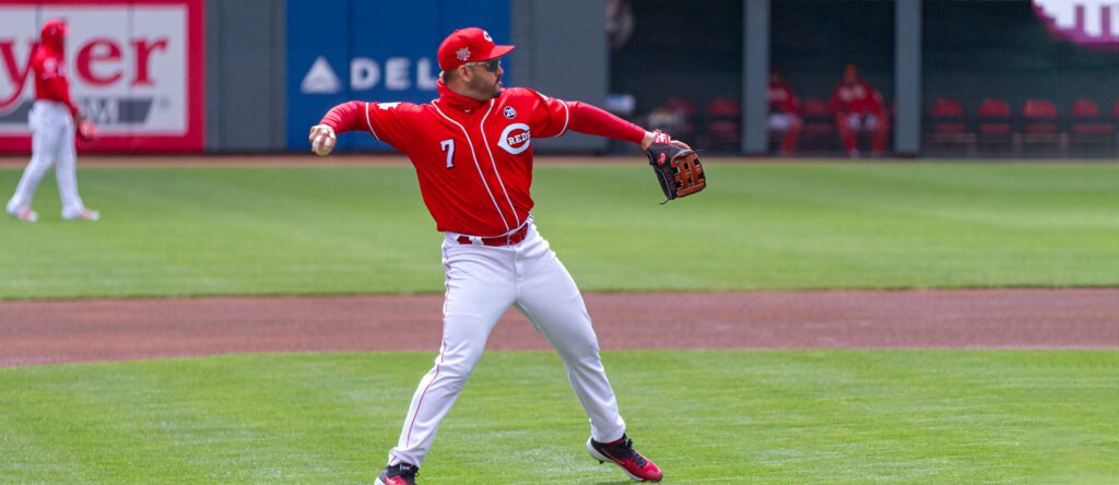 Eugenio Suárez pitching in red Cincinnati Reds uniform on green baseball field intense game Wallpaper