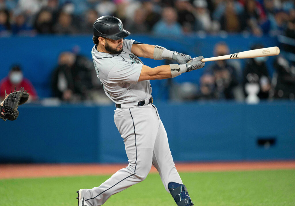 Eugenio Suárez mid-swing in gray baseball uniform with blurred stadium crowd background Wallpaper