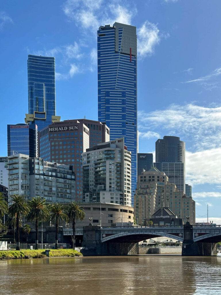 Eureka Tower with Melbourne skyline Yarra River and palm trees under clear blue sky wallpaper
