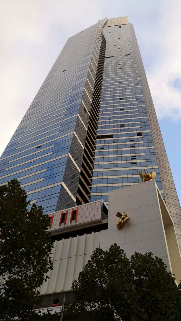 Eureka Tower Melbourne modern architecture reflective glass golden accents with green trees background Wallpaper