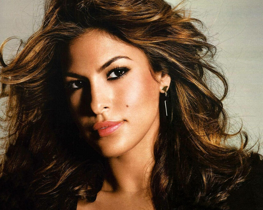 Close up of Eva Mendes with flawless skin flowing hair confident gaze against wallpaper background