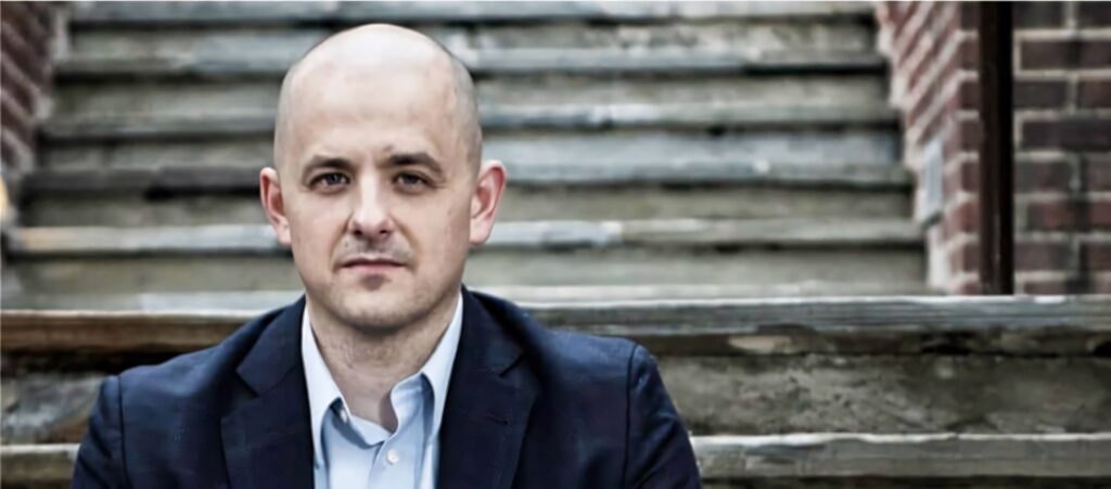 Evan McMullin professional portrait in dark suit on rustic stone steps with natural cool lighting Wallpaper
