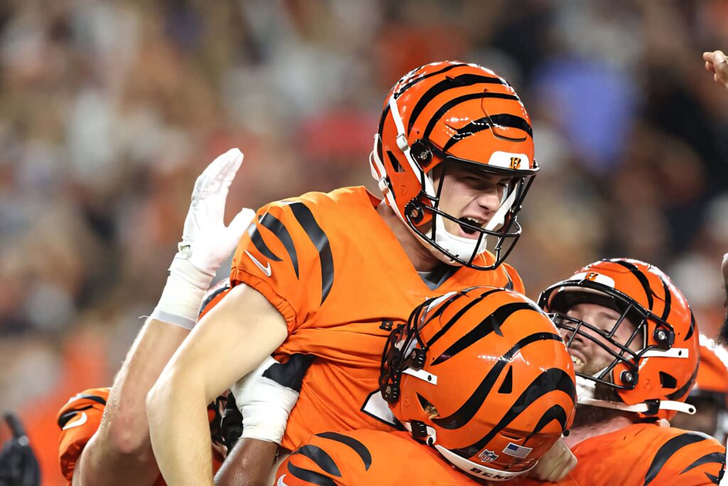 Evan McPherson celebration lifted by Bengals teammates vibrant orange black uniforms football game Wallpaper