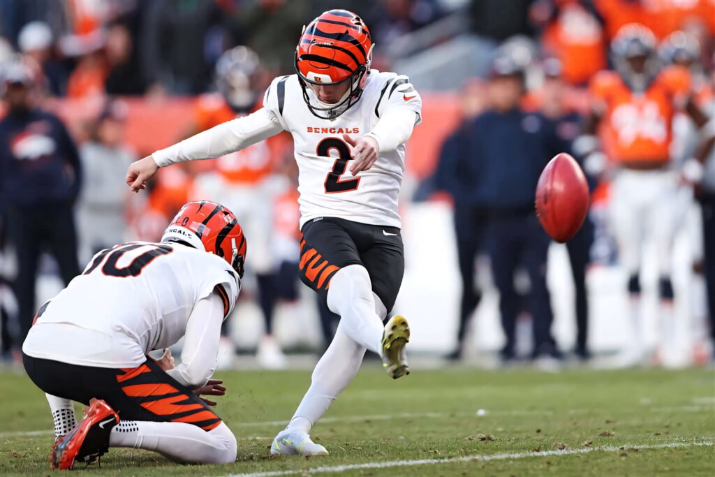 Evan McPherson kicking football in Cincinnati Bengals uniform mid-game vibrant dynamic action Wallpaper