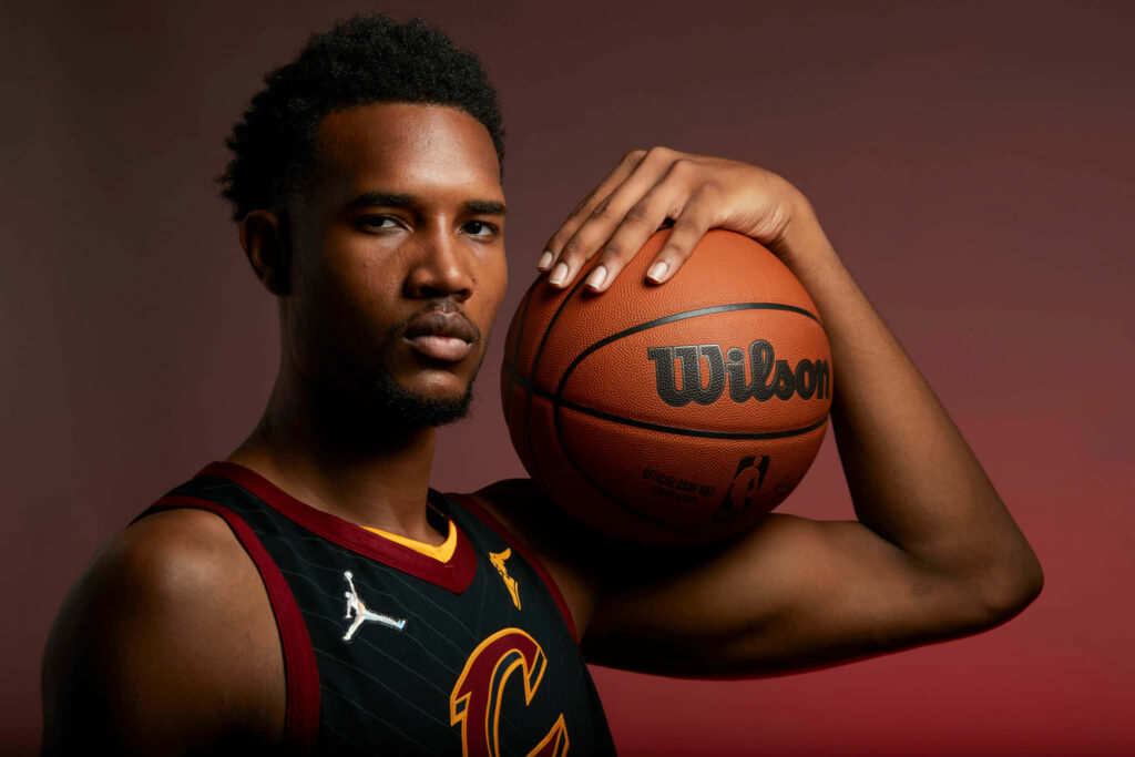 Evan Mobley in Cleveland Cavaliers jersey holding Wilson basketball with focused expression Wallpaper