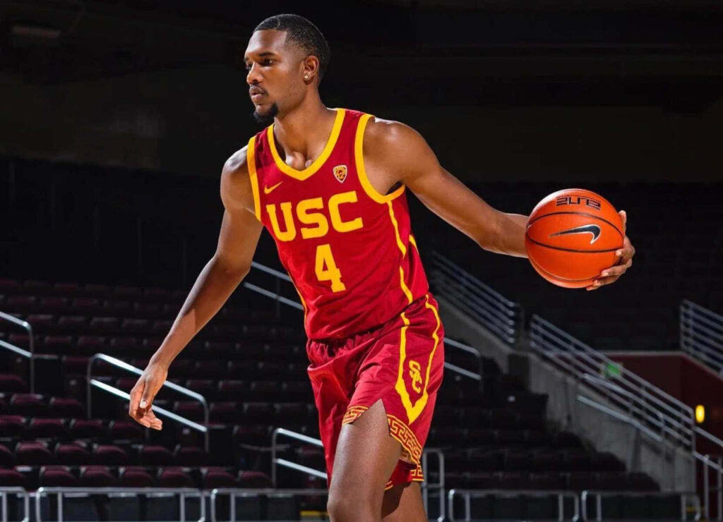 Evan Mobley in USC basketball uniform dribbling under bright stadium lights showing focus and skill Wallpaper