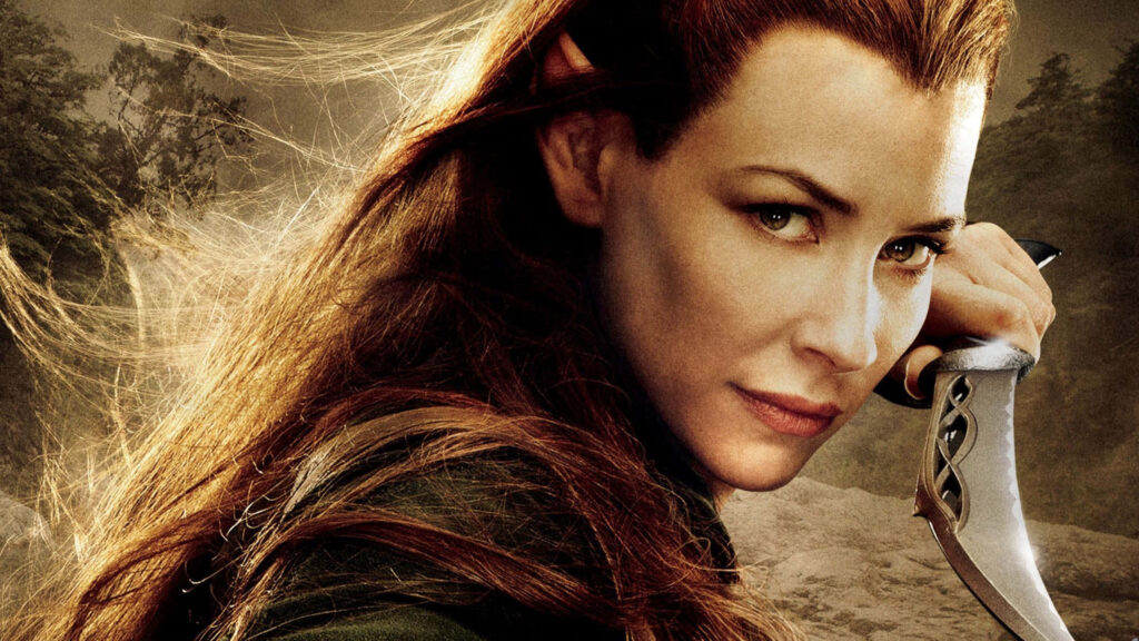 Evangeline Lilly as elf warrior in fantasy armor with weapon in golden forest background wallpaper