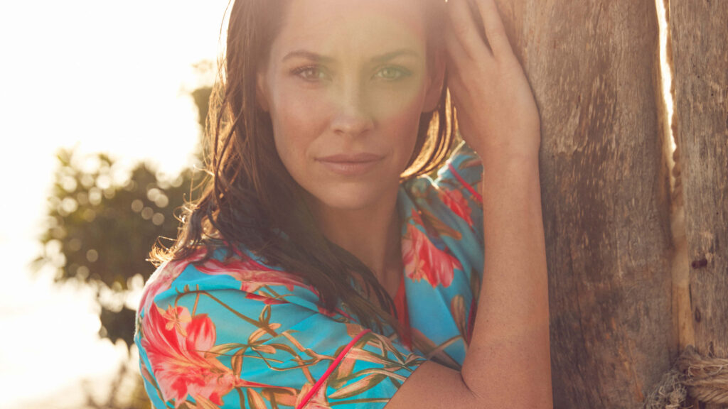 Evangeline Lilly in vibrant floral shirt by sunlit tree with warm natural outdoor background Wallpaper
