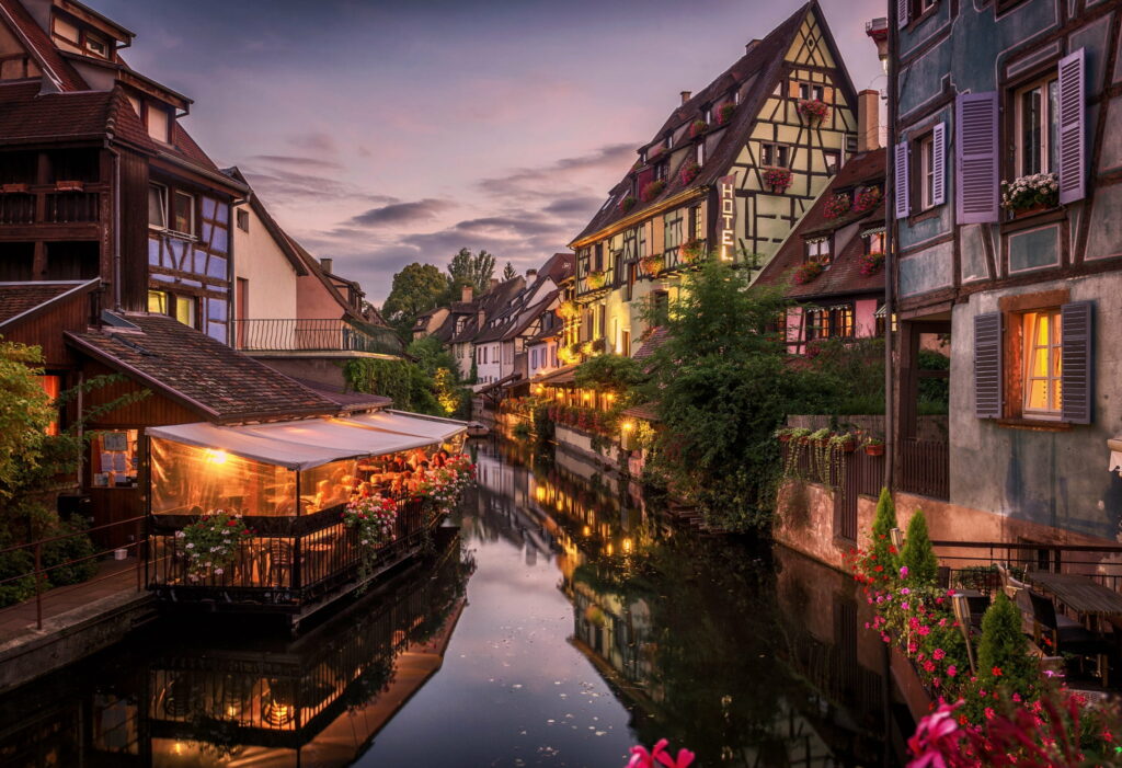 Evening Bliss in Colmar: A Charming Canal-side Café Scene Wallpaper