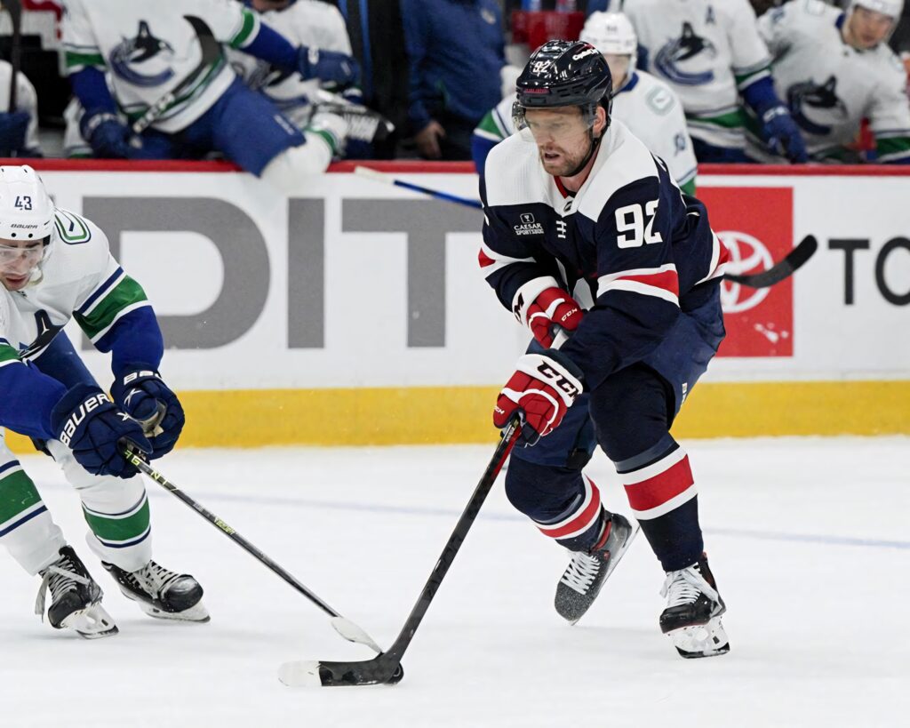 Evgeny Kuznetsov skating with puck in team uniform during intense hockey game action wallpaper