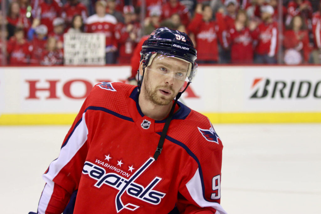 Evgeny Kuznetsov in red Washington Capitals jersey playing hockey with cheering crowd background Wallpaper