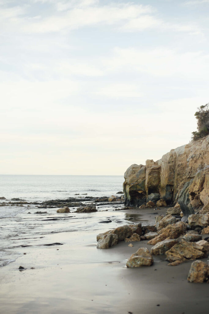 Majestic Malibu: Stunning Beach Shore with Striking Rock Formations Wallpaper