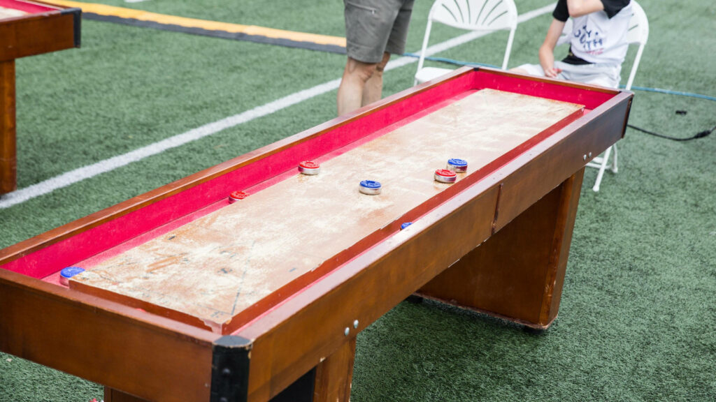 Exciting Shuffleboard Wallpaper: Wooden Table & Colorful Pucks