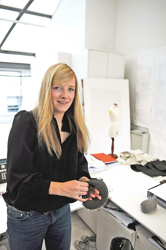 Confident executive in Alexander McQueen inspired attire in a modern creative workspace background Wallpaper