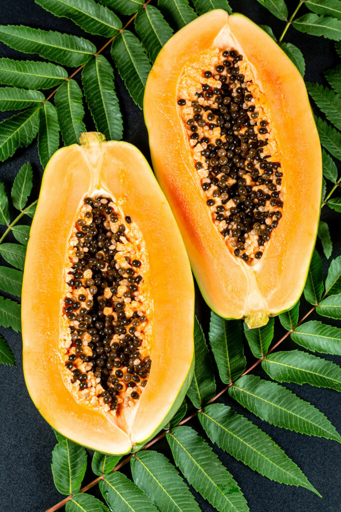 Tropical Papaya Wallpaper: Ripe Halves & Lush Green Leaves