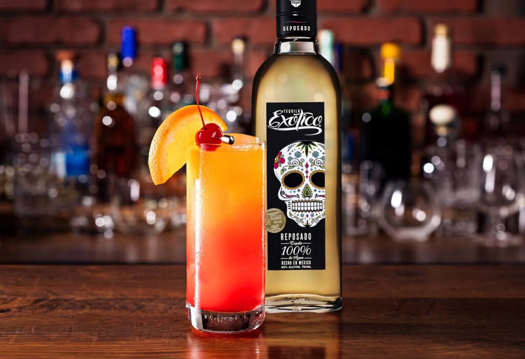 Exotico Tequila Reposado bottle with skull label and colorful cocktail on wooden bar counter Wallpaper