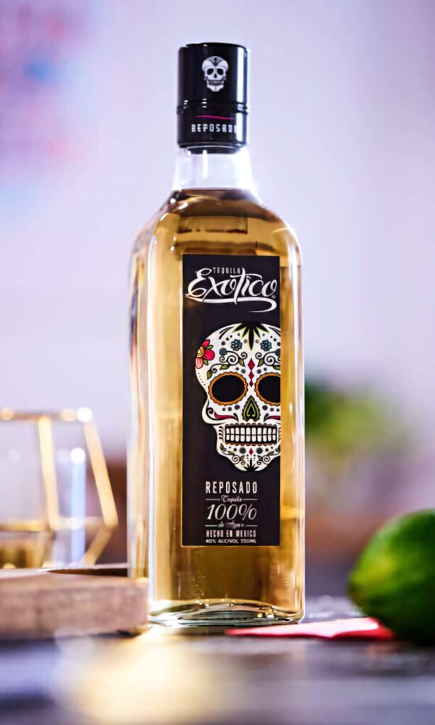 Exotico Tequila Reposado bottle with golden hue and colorful sugar skull label on warm background Wallpaper