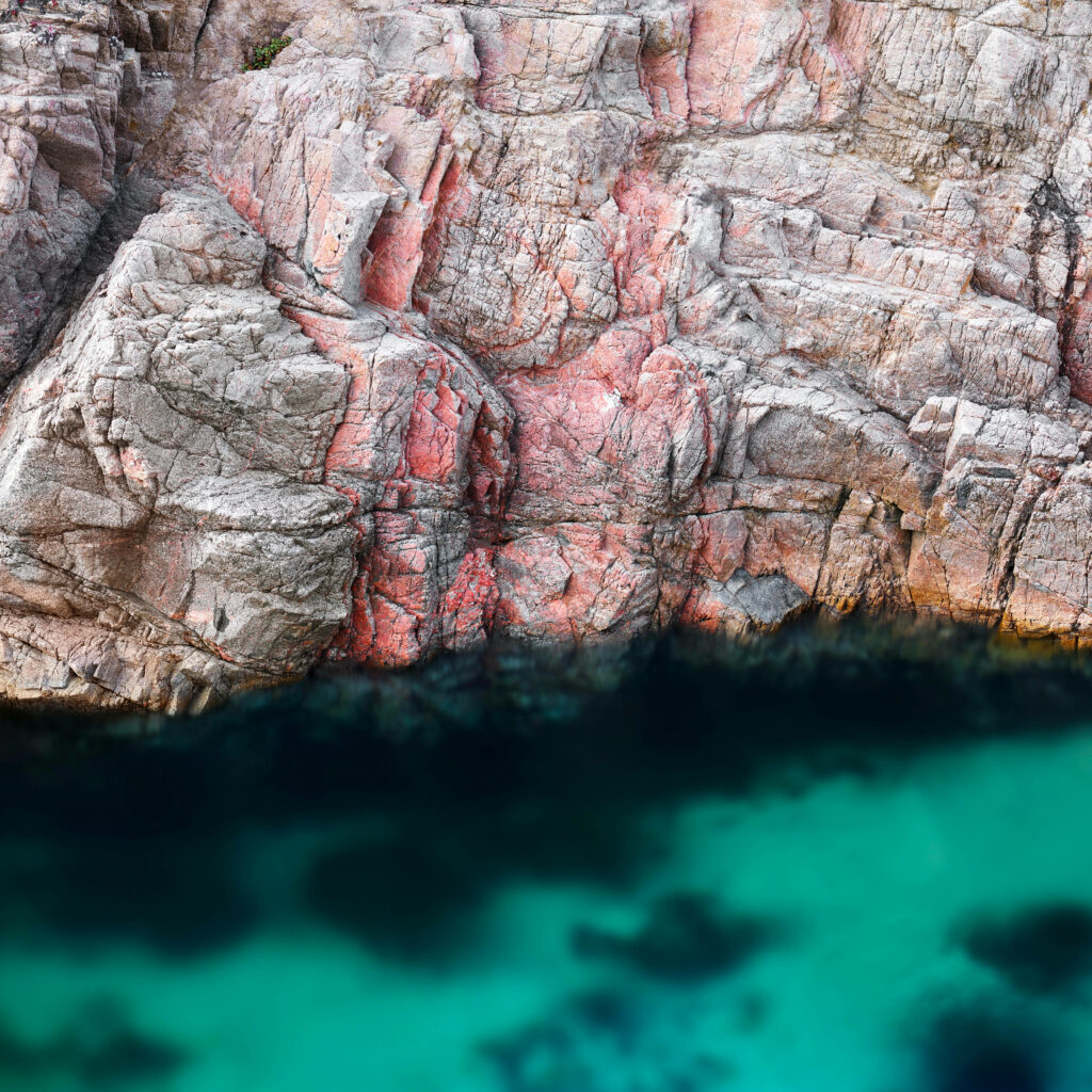 Jagged reddish grey cliffs meet deep turquoise coastal waters Big Sur macOS wallpaper nature view