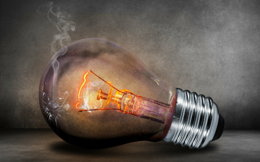 3D shattered glowing light bulb with smoke and orange filament on dark concrete background wallpaper