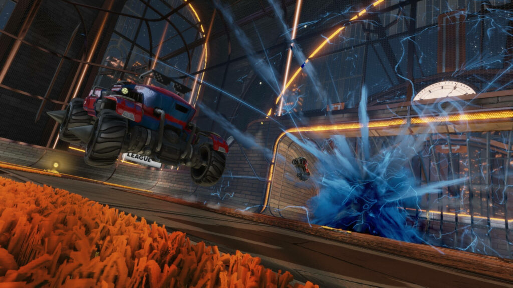 Explosive Encounter on the Rocket League Battlefield: Blue Fireball Rockets through Opposition's Goal, Accompanied by Red Racer with Mammoth Wheels Wallpaper