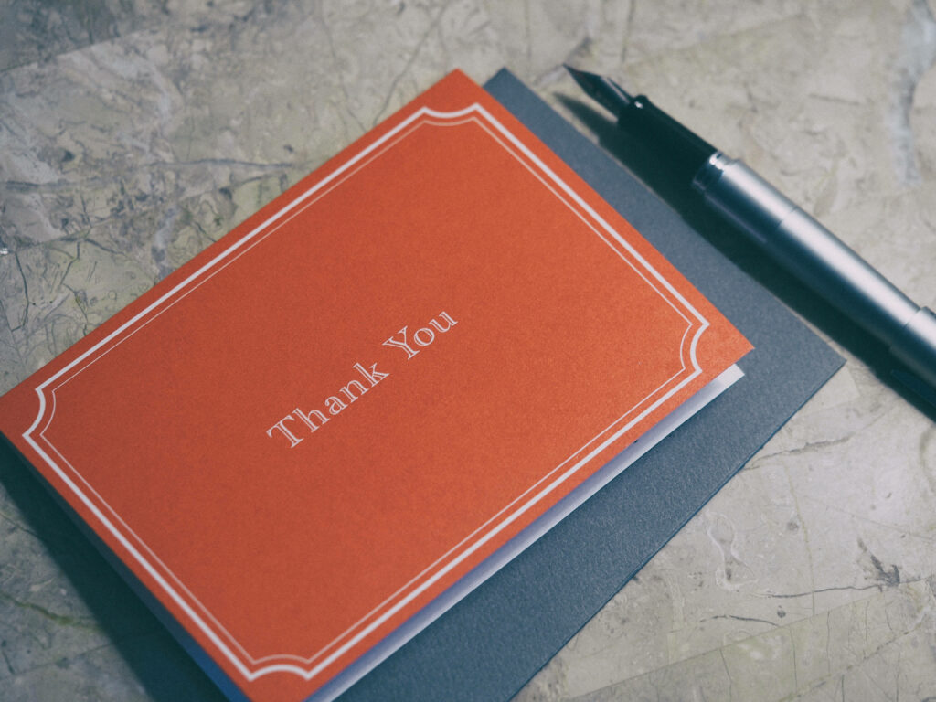 Expressing Gratitude: A Vibrant Orange Thank You Notebook on Wallpaper