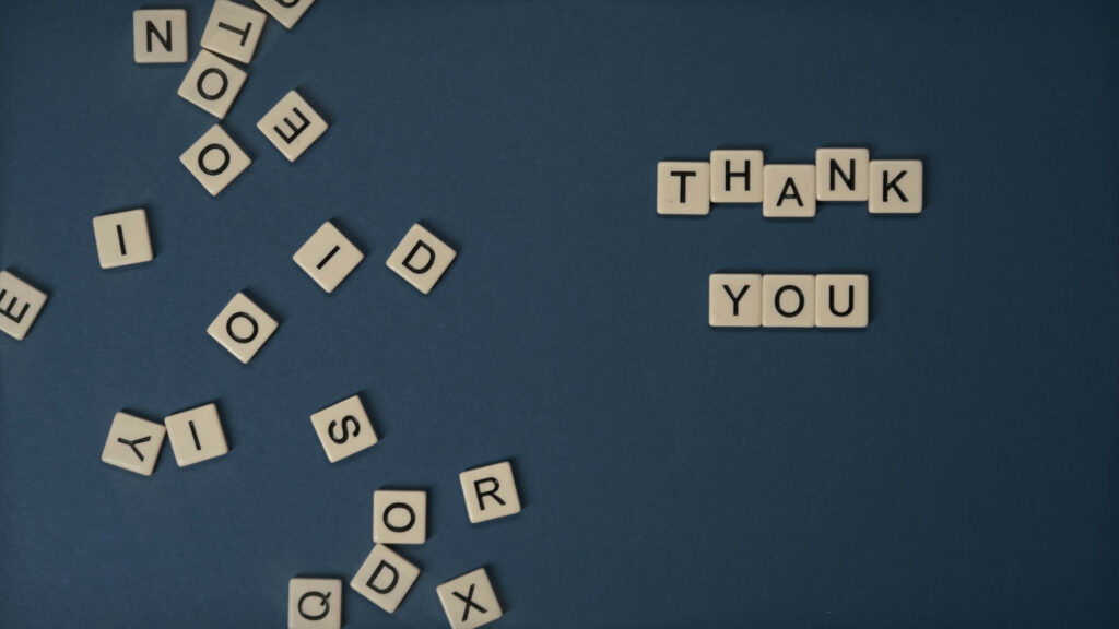 The Art of Gratitude: Saying Thank You with Scrabble Cubes on a Dark Blue Wallpaper'