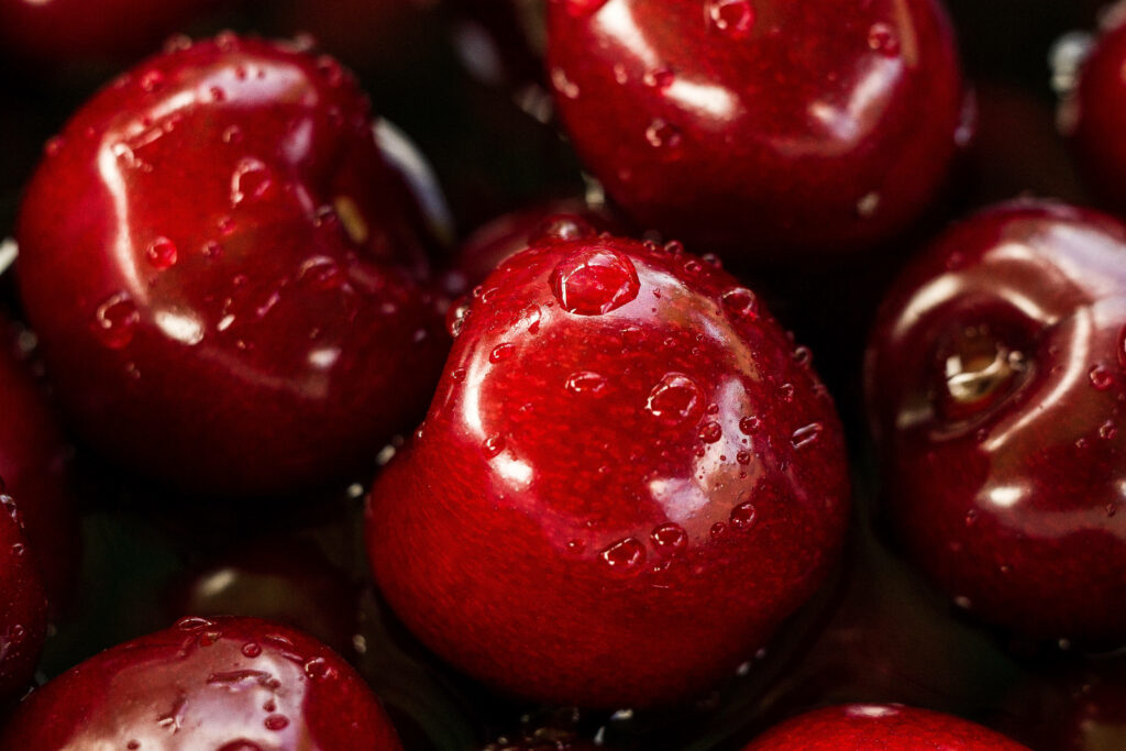 Close-up: Luscious Red Cherries Glistening under Golden Sunlight Wallpaper