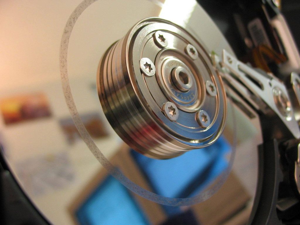 Extreme close-up of hard drive disk and spindle showcasing metallic motor hub and platter Wallpaper