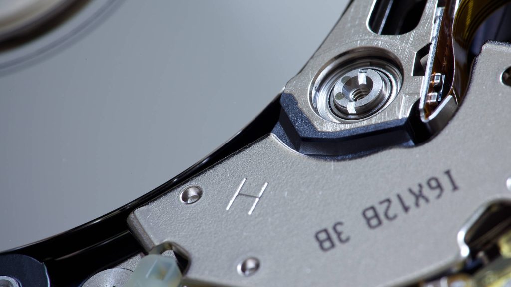 Extreme close up of a hard drive platter and actuator detailed mechanical HDD wallpaper background