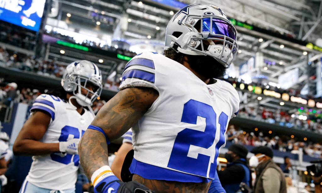 Ezekiel Elliott running on field in Dallas Cowboys blue white uniform with helmet and visor Wallpaper